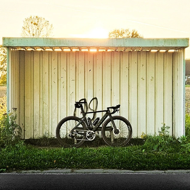 Rennrad vor einem Wartehäuschen im Abendlicht