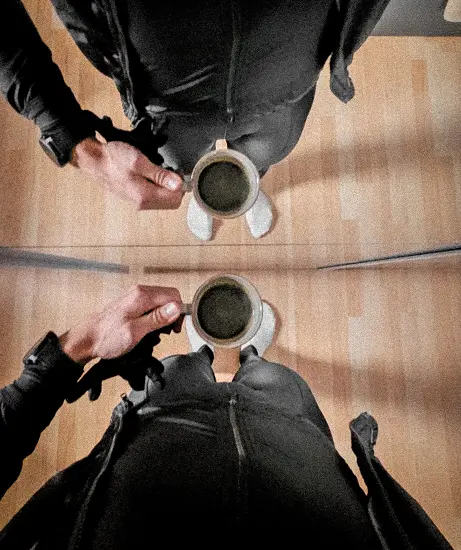 Athlet in warmer Sportkleidung mit einer Tasse Kaffee vor dem Training